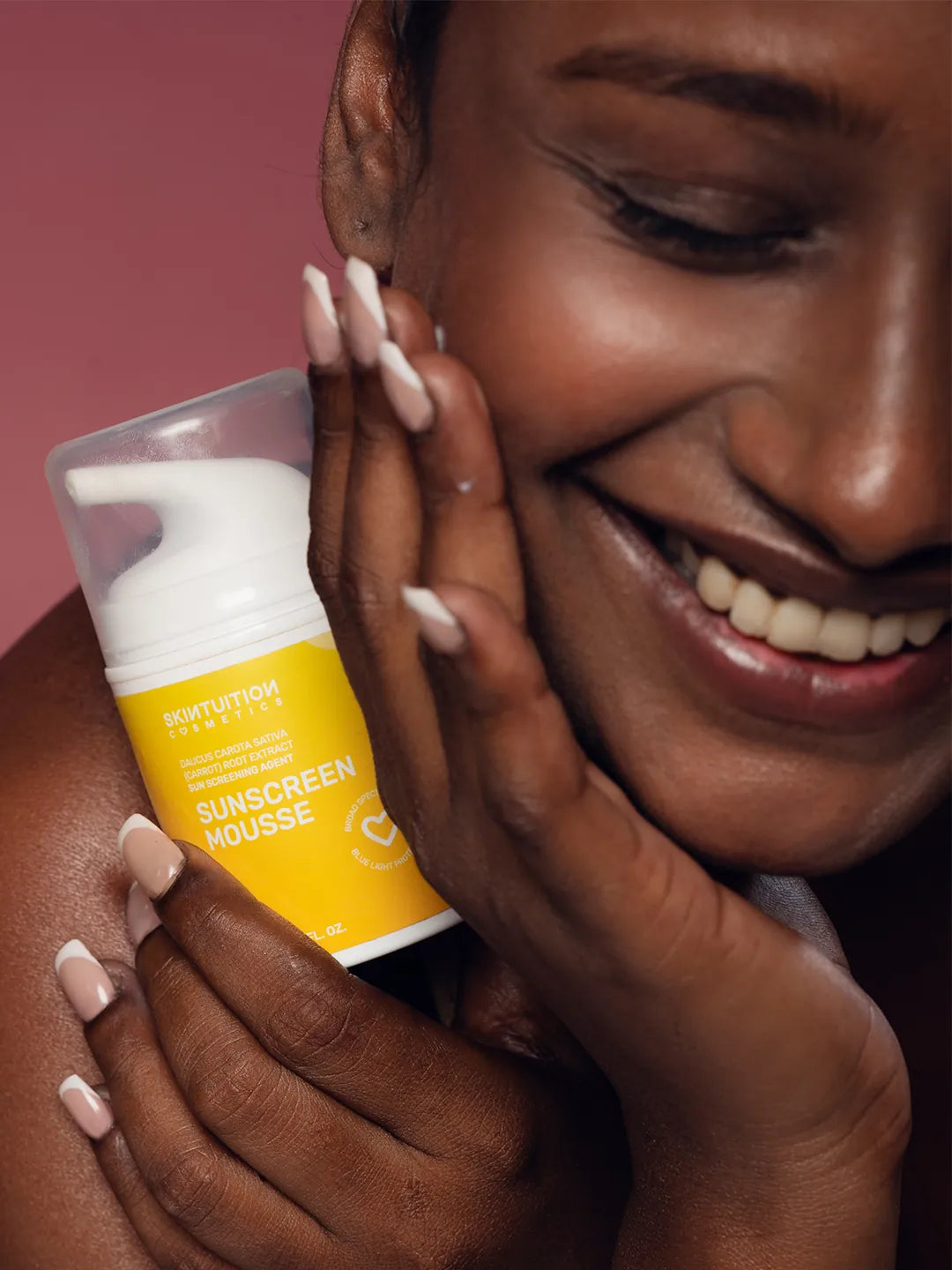 Dark skin model holding Skintuition Cosmetics sunscreen mousse